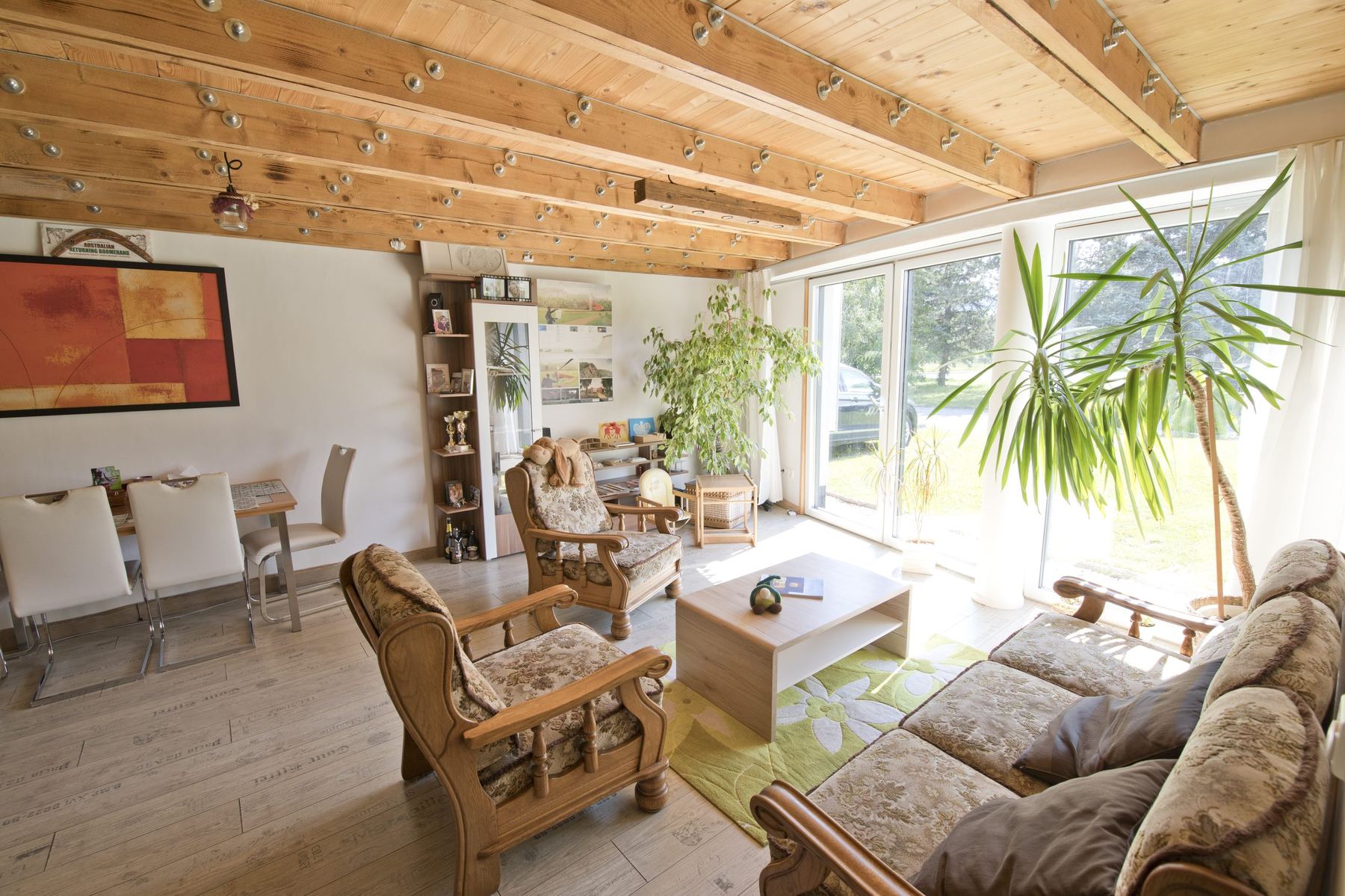 Living room of an earth-sheltered house with wood-beamed ceiling and glass doors opening to a lawn